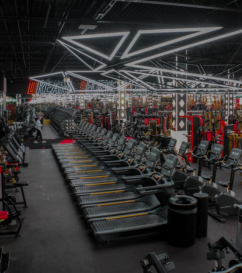 Wide view of the Absolute Recomp Arlington cardio floor with treadmills, strength equipment, and overhead LED lighting