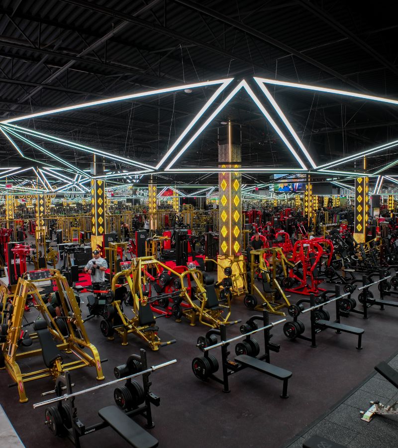 Wide view of the Absolute Recomp Arlington gym floor with strength equipment, benches, and overhead LED lighting