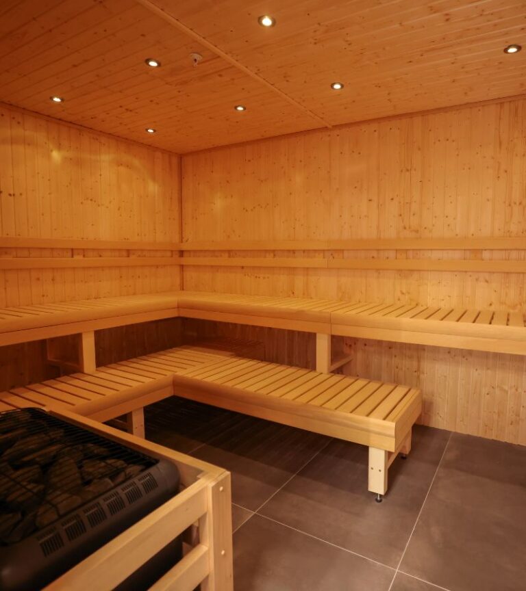 Spacious wood sauna room with benches at Absolute Recomp Arlington.