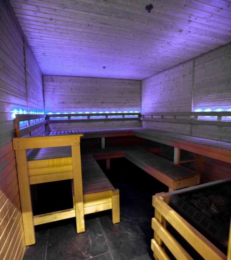 Absolute Recomp Fort Worth sauna recovery room with wood seating and LED lighting for post-workout relaxation.