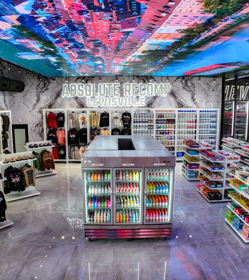 Absolute Recomp Lewisville retail store with gym supplements, protein drinks, and branded apparel including shirts, hats, and accessories.