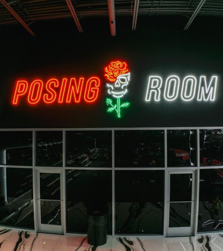 Absolute Recomp posing room with neon skull and rose sign in red green and white lights