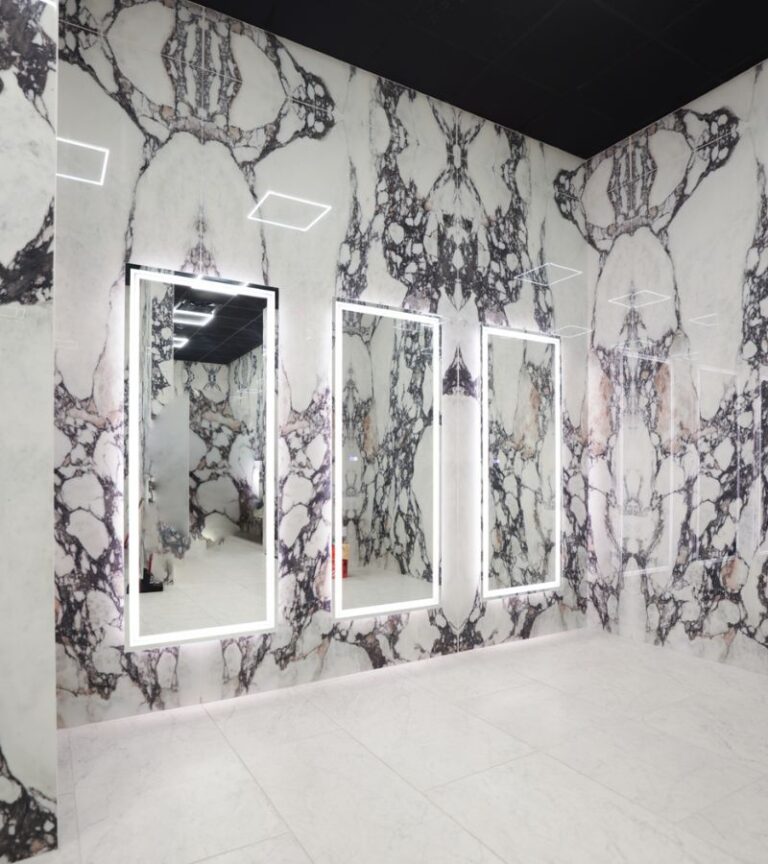 Absolute Recomp gym locker room with marble walls, illuminated mirrors, and sleek modern design